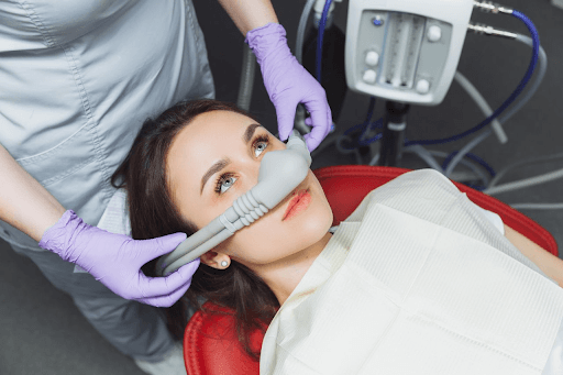 a woman is receiving laughing gas sedation before her dental procedure